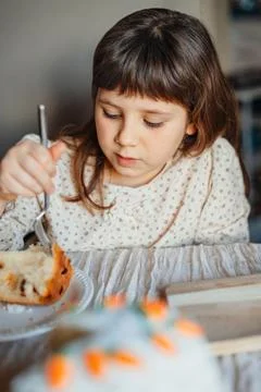 Child eating easter cake at the table. Stock Photos