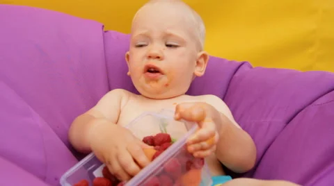 Child Eating Fruit Lying in an Easy Chair Stock Footage 64764588
