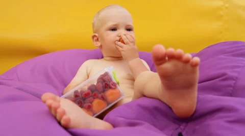Child Eating Fruit Lying in an Easy Chair Stock Footage 64764617