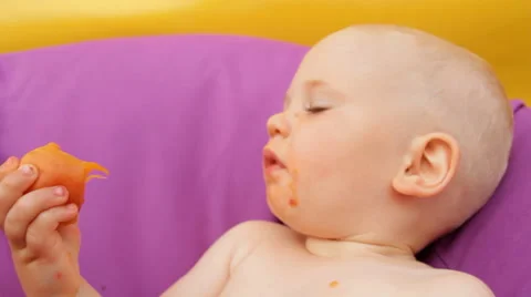 Child Eating Fruit Lying in an Easy Chair Stock Footage 64764631