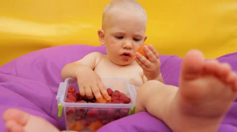 Child Eating Fruit Lying in an Easy Chair Stock Footage 64767140
