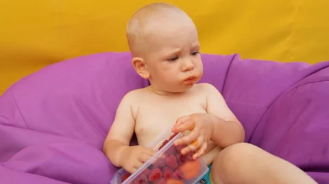 Child Eating Fruit Lying in an Easy Chair Stock Footage 64767193
