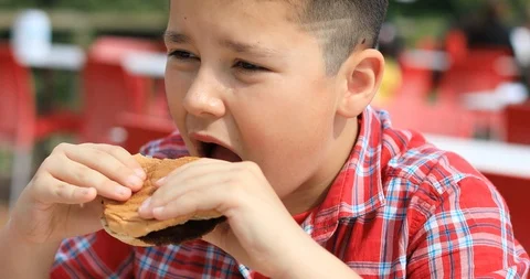 Child eating hamburger at the restaurant Stock Footage 105475770