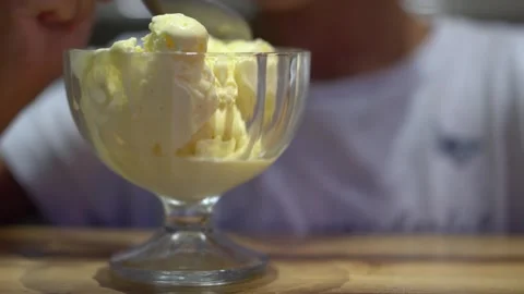 The child is eating a large portion of vanilla ice cream with a spoon. Video stock 251723842