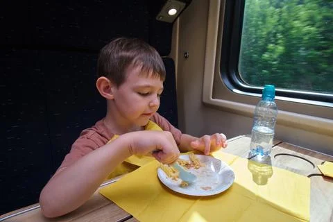 Child eating lunch on train while traveling. Boy sitting in passenger carri.. Stock Photos