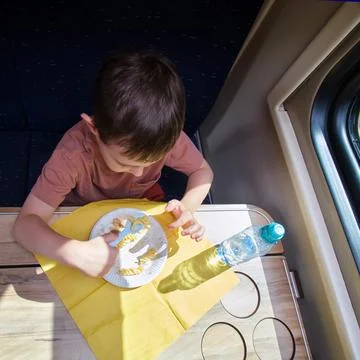 Child eating pasta at table inside moving passenger train. Young boy having.. Stock Photos
