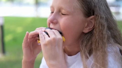 The child eats a black burger on the street. Stock Footage 248607802