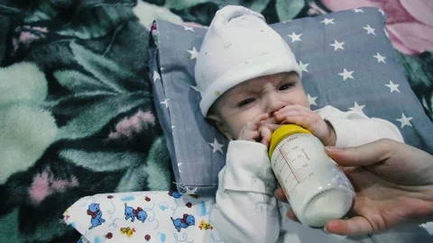The child eats from a bottle. Spits out the milk and reaches for the bottle Stock Footage 102032070