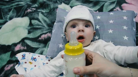 The child eats from a bottle. Spits out the milk and reaches for the bottle Stock Footage 102032132