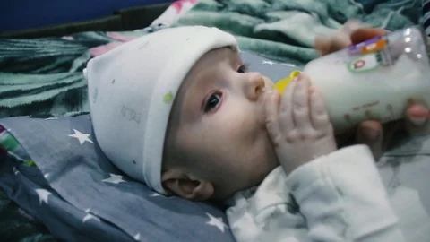 The child eats from a bottle. Spits out the milk and reaches for the bottle Stock Footage 102032140