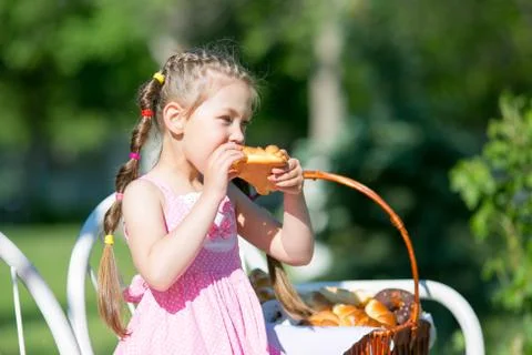 The child eats bread from a large basket. Foto stock