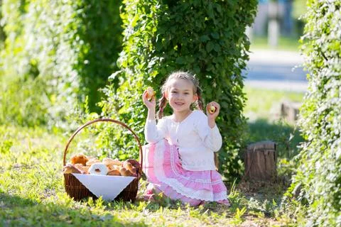 The child eats bread from a large basket. Stock Photos
