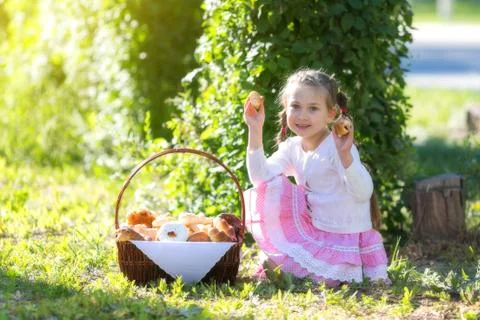 The child eats bread from a large basket. Stock Photos