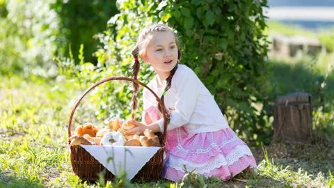 The child eats bread from a large basket. Stock Photos
