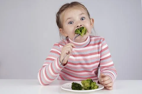 The child eats broccoli with an appetite. Organic Cabbage and food on a plate Stock Photos