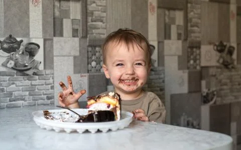 The child eats a cake and shows emotions. Stock-Fotos