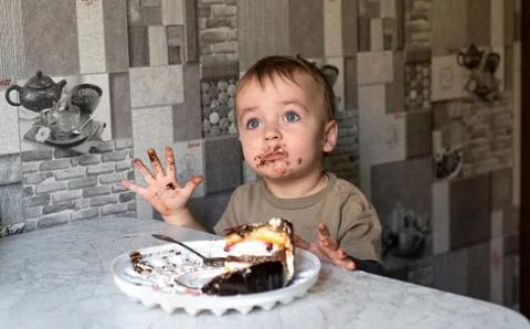 The child eats a cake and shows emotions. Foto stock