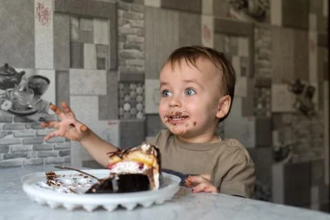 The child eats a cake and shows emotions. Stock-Fotos