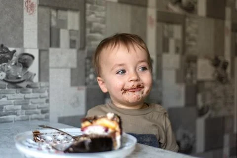 The child eats a cake and shows emotions. 스톡 사진