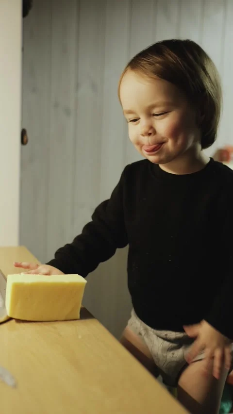 The child eats cheese. She shows that it is very tasty. The girl happily enjoys Video stock 321944241