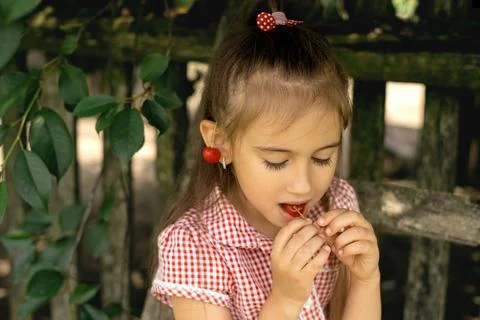 The child eats cherries with his eyes closed. Stock Photos