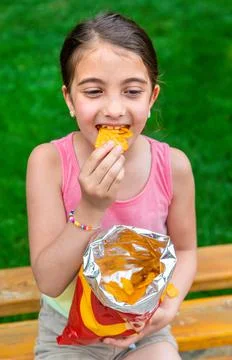 The child eats chips in the park. Selective focus. Stock Photos