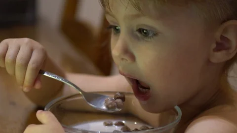 A child eats chocolate balls with milk and watches cartoons Stock Footage 113222307