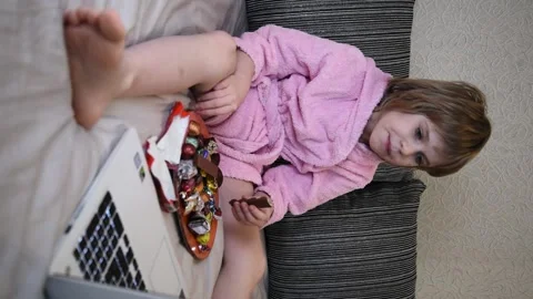 The child eats chocolate candies with pleasure. The girl is sitting comfortably Stock Footage 146836686