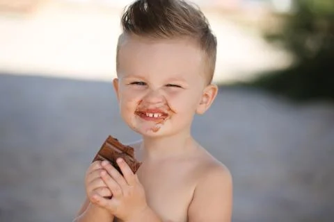 Child eats chokolate with full stength on a beach Stock-Fotos