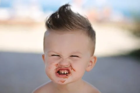 Child eats chokolate with full stength on a beach Stock Photos