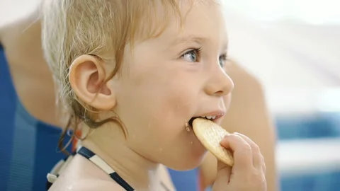 The child eats cookies. The child after eating in the pool eats cookies. Stock Footage 116014413