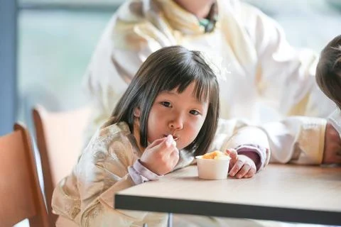 Child eats dessert at table, smiling softly Stock Photos