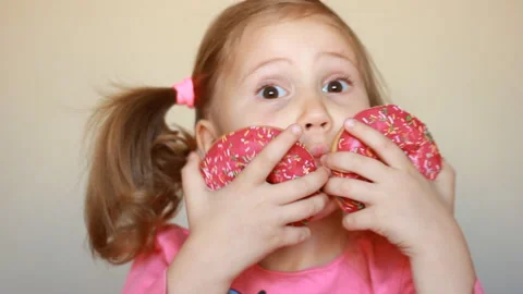 Child eats donut. Closeup baby girl eating doughnut with glase. Delicious, sweet Stock Footage 120988121