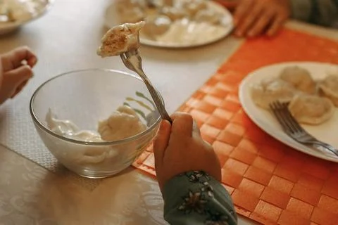 The child eats freshly prepared dumplings from a glass plate. Stock Photos