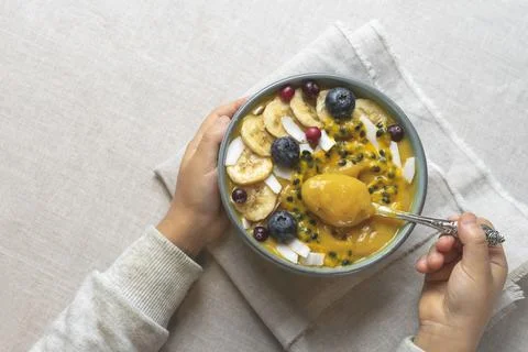 The child eats fruit puree.Children's hands hold a spoon and a bowl of smoothies Stock Photos