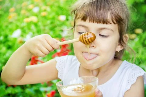 The child eats honey. Selective focus. nature. Stock Photos