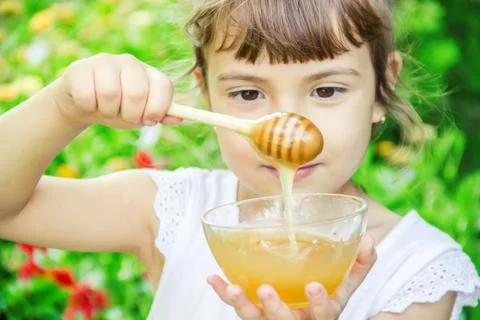 The child eats honey. Selective focus. nature. Stock Photos