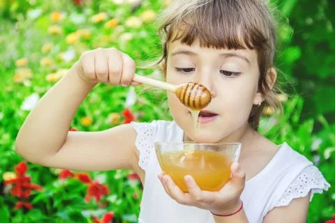 The child eats honey. Selective focus. nature. Stock Photos