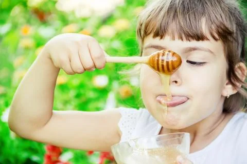 The child eats honey. Selective focus. nature. Stock Photos