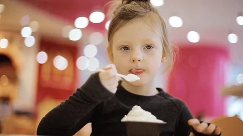 The child eats ice cream in a cup while sitting in a cafe. Close-up. Stock Footage 101054542