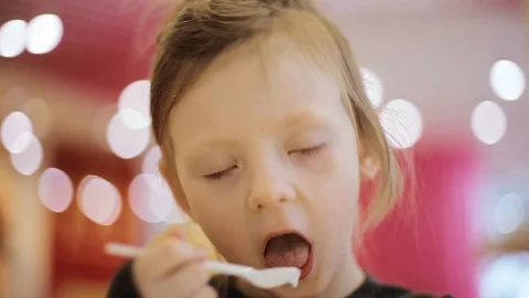 The child eats ice cream in a cup while sitting in a cafe. Close-up. Video stock 101054568