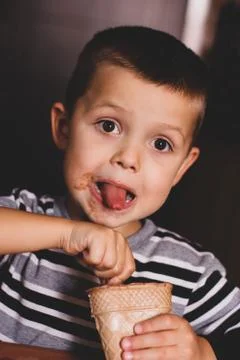The child eats ice cream with a spoon. The child shows his tongue. Boy Stock Photos