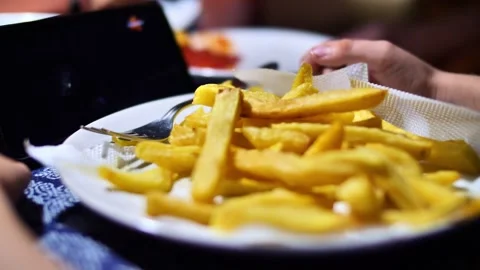 Child eats junk food and watches cartoons on the phone Stock Footage 258497156