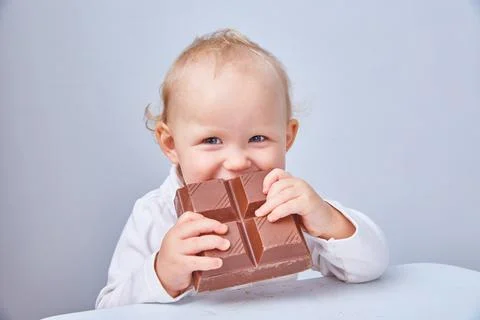 Child eats a large piece of chocolate. The concept of a junk food and healthy Stock Photos