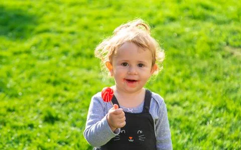 A child eats a lollipop in the park. Selective focus. Stock Photos
