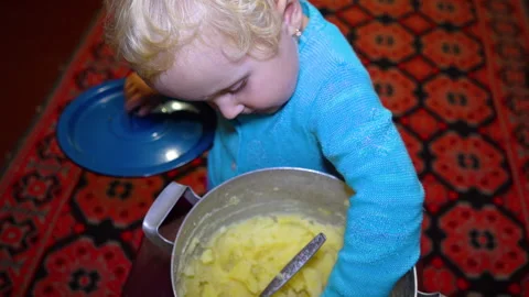 Child eats mashed potatoes from a saucepan with his hands Stock Footage 333299512