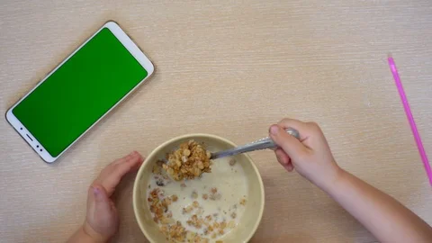 The child eats muesli with milk. Above view. Stock Footage 106437642
