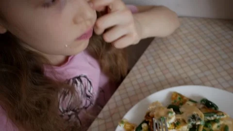 Child eats omelet with vegetables in several pieces close up. Baby girl is hungr Stock Footage 271480280