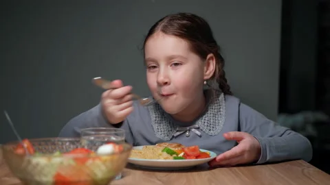 The child eats pasta with a fresh salad of tomato, pepper and round cheese. 4K Stock Footage 152408116