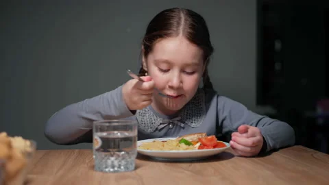 The child eats pasta with a fresh salad of tomato, pepper and round cheese. 4K Stock Footage 152419327
